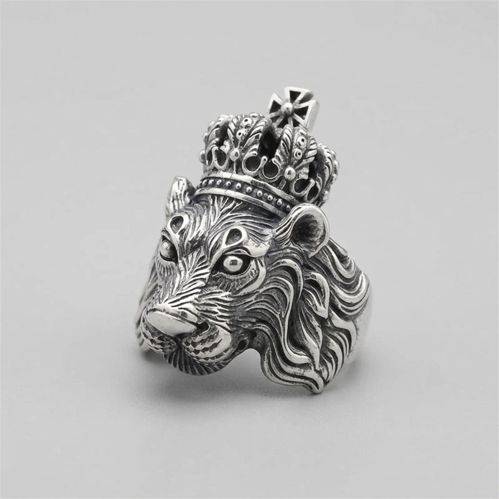 A silver lion head ring with a crown, shown worn on a finger.