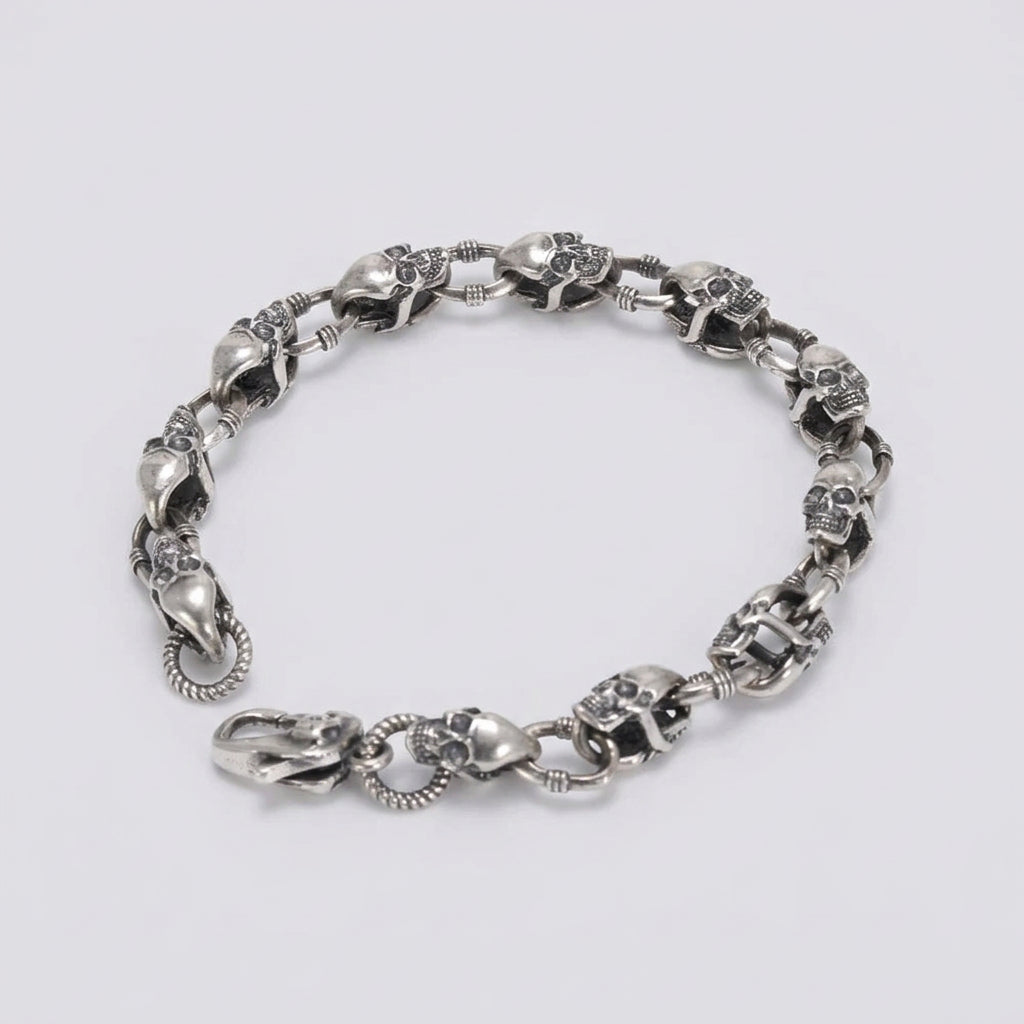 Silver bracelet with skull designs on a black background