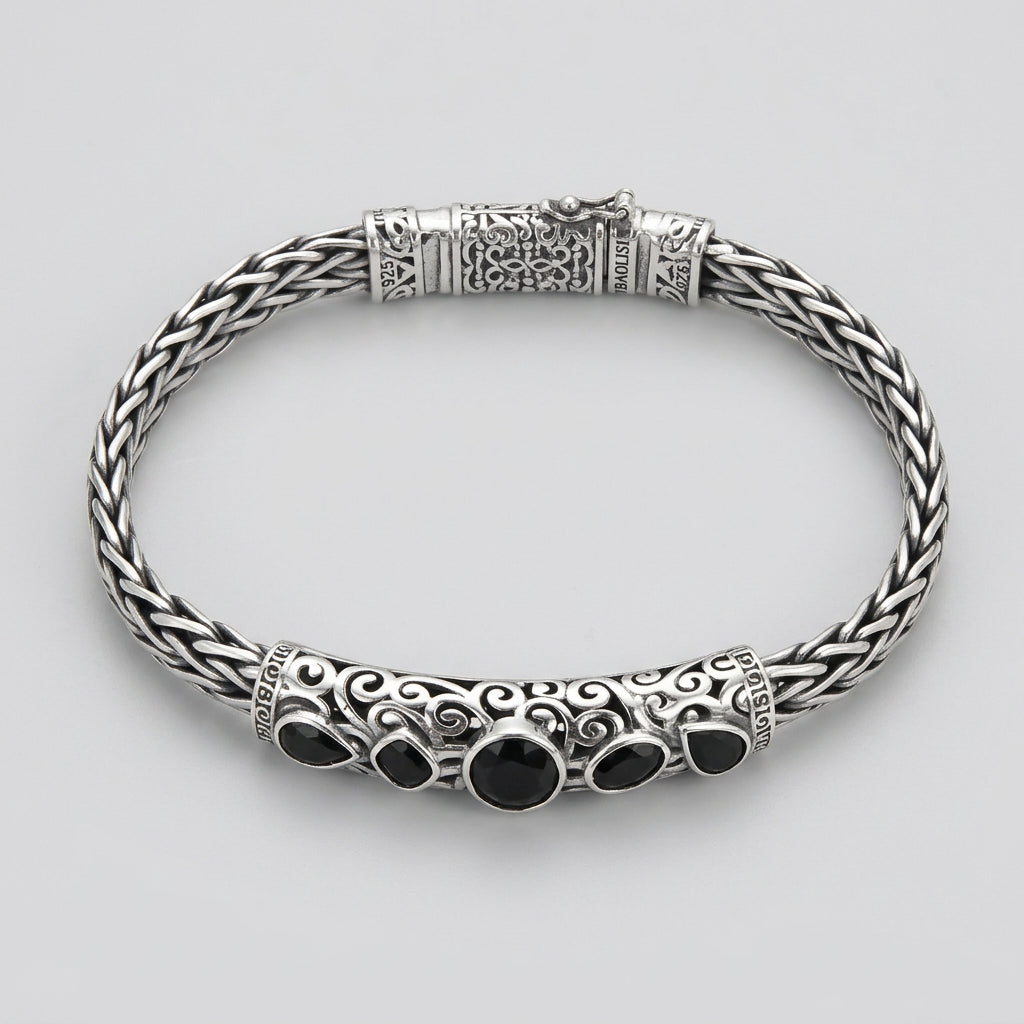 Silver bracelet with black stones on a wooden surface
